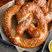 A close up of a J & J SuperPretzel Bavarian Sourdough soft pretzel with salt on top.