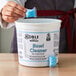A white tub of Noble Chemical QuikPacks with blue text and a blue bowl cleaner pack inside.