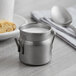 A stainless steel Vollrath mini milk can with milk in it.