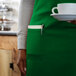 A woman in a green Choice bib apron holding a cup of coffee.