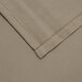 A close up of a beige fabric table cover with a white hem.