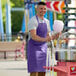 A man wearing a bright purple Choice apron smiling at the camera while making cotton candy.