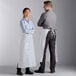 A man and woman wearing white Choice poly-cotton bistro aprons with one pocket.