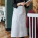 A woman wearing a white Choice bistro apron taking an order.