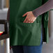 A person wearing a Choice hunter green cobbler apron with pockets.