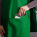 A person wearing a green Choice cobbler apron with pockets.