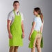 A man and woman wearing lime green bib aprons.