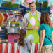 A man and a woman wearing lime green Choice Poly-Cotton Standard Bib Aprons holding cotton candy.