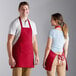 A man and woman wearing red Choice aprons standing next to each other in a professional kitchen.