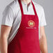 A man wearing a red Choice poly-cotton bib apron with 3 pockets.