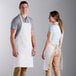 A man and woman wearing white Choice standard bib aprons with pockets.