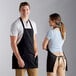 A man and woman standing next to each other wearing black Choice front of house aprons.