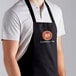 A man wearing a black Choice front of house bib apron with 3 pockets.
