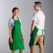 A man and woman wearing Choice Kelly Green adjustable bib aprons.