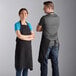 A man and woman wearing Choice black aprons in a professional kitchen.