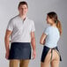 A man and woman wearing Choice navy blue standard waist aprons.