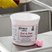 A white container with a pink label of Noble Chemical QuikPacks on a metal surface.