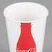 A white paper cup with a red Coca-Cola bottle logo.