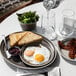 A Libbey matte olive porcelain oval platter with eggs, bacon, and toast on a table.