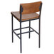A BFM Seating Memphis wooden and metal counter height stool with a wooden back and seat and metal legs.