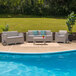 A light gray faux rattan patio set with a couch and table on a patio.