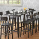 A Lancaster Table & Seating rustic industrial trestle table base for a restaurant table with wine glasses and chairs.