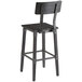 A black Lancaster Table & Seating bar chair with a wooden seat and back.