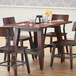 A Lancaster Table & Seating wooden trestle table base for a dining table with chairs and glasses on it.