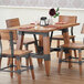 A Lancaster Table & Seating wooden trestle table base with chairs and glasses on it.