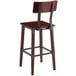 A Lancaster Table & Seating Rustic Industrial bar stool with a mahogany finish and metal backrest.