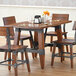 A Lancaster Table & Seating solid wood dining table with chairs and wine glasses on it.