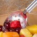 A stainless steel perforated spoon with fruit on it.