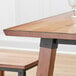 A Lancaster Table & Seating solid wood dining table with trestle legs and a glass on it.