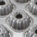A close-up of a Chicago Metallic silver aluminized steel bundtlette cake pan with several mini cakes in it.