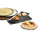 A group of Libbey brown speckled stone trays with cheese, crackers, and other food on them.