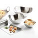 A group of Libbey brushed metal bowls with food on a table.