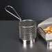 A Libbey stainless steel fry presentation basket with French fries.