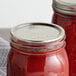 Two Ball wide mouth canning jars filled with red liquid with Ball wide mouth lids.