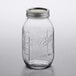 A Ball clear glass quart mason jar with a silver metal lid on a table.