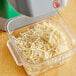 A plastic container filled with shredded cheese using an AvaMix 3/16" grating disc.