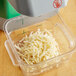 A close-up of a grey AvaMix Revolution grating and shredding disc for a food processor with shredded cheese on it.