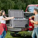 A man and woman loading CaterGator outdoor coolers into a truck.