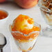 A glass cup with a scoop of ice cream and orange I. Rice Mango Sunrise topping.