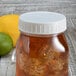A Fineline Mason jar lid on a jar of lemonade with ice and a lemon.