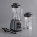 An AvaMix commercial blender with a clear Tritan container and a black lid sitting on top of another.