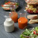A table with food in Fineline containers including a salad and a sandwich.