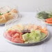 A Durable Packaging round foil catering tray holding three clear plastic containers of food.
