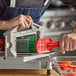 A man using a red Prince Castle Vegetable Cutter Brush to clean a vegetable cutter.