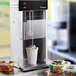 A Vitamix countertop frozen dessert mixer with a cup of ice cream and candy in it.