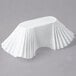 A white paper fluted food tray with pleated ruffled edges.